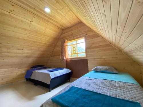 Saboyá的住宿－Cabaña campestre en Chiquinquirá，小木屋内的两张床,设有窗户