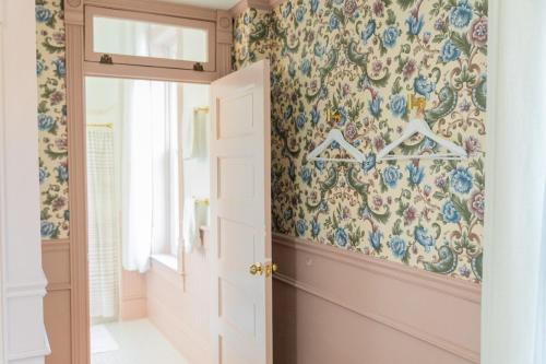 un pasillo con papel pintado con motivos florales y una puerta abierta en Suite 4 Historic Art City Inn, en Springville