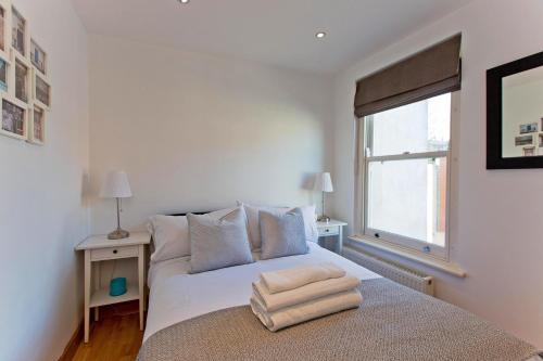a white bedroom with a bed and a window at Convenient 1 bedroom apartment with parking in London