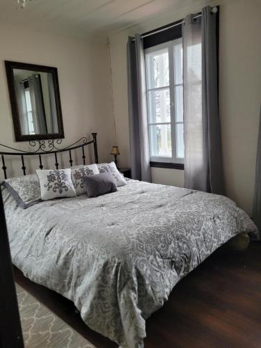 Schlafzimmer mit einem Bett, einem Spiegel und einem Fenster in der Unterkunft Om Villégiature in Saint-Laurent-de-l'ile d'Orleans