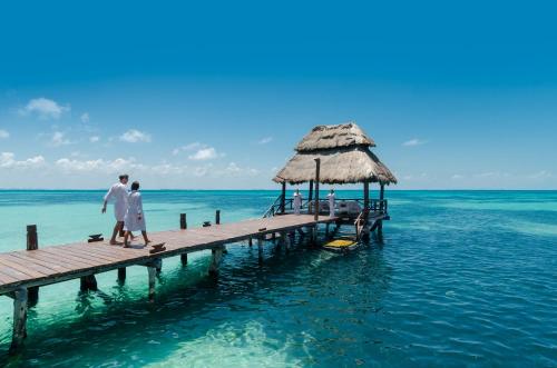 two people walking on a dock in the water at Mia Reef Isla Mujeres - All Inclusive Resort in Isla Mujeres