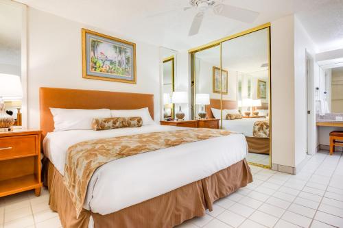 Maui Schooner Resort في كيهي: غرفة نوم بسرير كبير ومرآة كبيرة