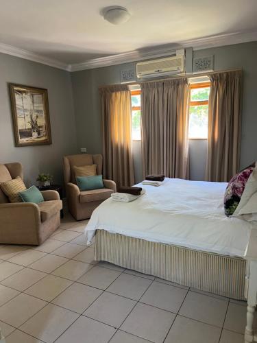 a bedroom with a large bed and two chairs at The Vic 1906 Self Catering Units in Montagu