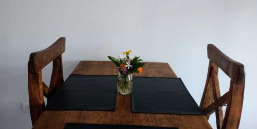 a wooden table with a vase of flowers on it at ABBA Departamento turistico in Trevelin