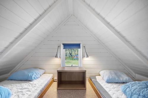 two beds in a white room with a window at First Camp Frigård Camping & Cottages in Kruså