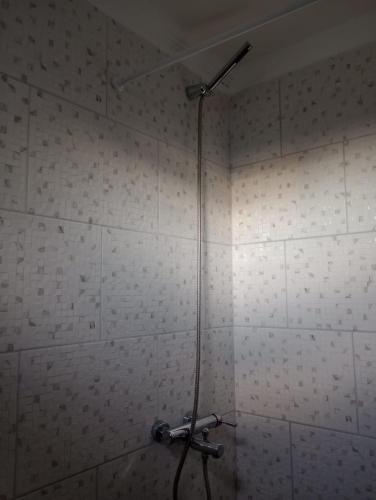 a shower in a bathroom with a white tiled wall at ABBA Departamento turistico in Trevelín