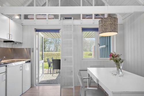 a kitchen with a table with a vase of flowers on it at First Camp Frigård Camping & Cottages in Kruså