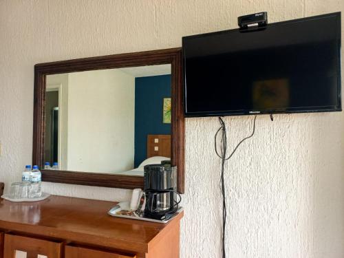 - une télévision murale à écran plat à côté d'un miroir dans l'établissement HOTEL TORRE MARINA, à Monte Gordo