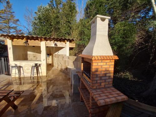 a brick fireplace on a patio with a table at Gîte de Valentin Moulin de Tartay en Avignon in Avignon