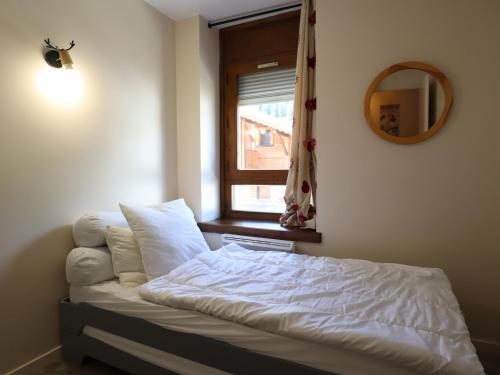 ein Bett in einem Schlafzimmer mit einem Spiegel und einem Fenster in der Unterkunft Appartement cosy dans le centre du village, proche pistes et ESF, avec balcon et équipements complets - FR-1-623-286 in Les Gets