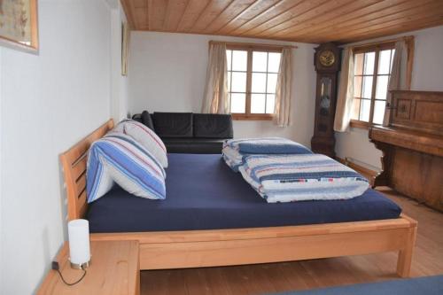 Ferienwohnung Mätzli في فيتزناو: غرفة نوم بسرير وملاءات زرقاء وأريكة