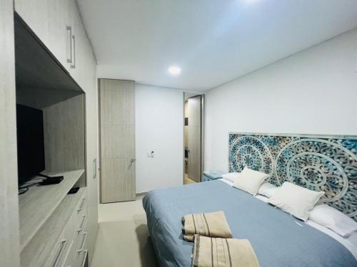 1 dormitorio con 1 cama azul y TV en Samaria Club de playa, Sector Pozos Colorados, en Santa Marta