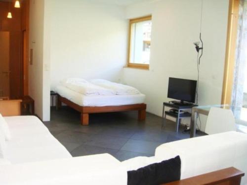 een kamer met een bed, een tafel en een tv bij La Montanella 7 in Maloja