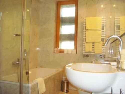 een badkamer met een wastafel, een douche en een bad bij La Montanella 7 in Maloja