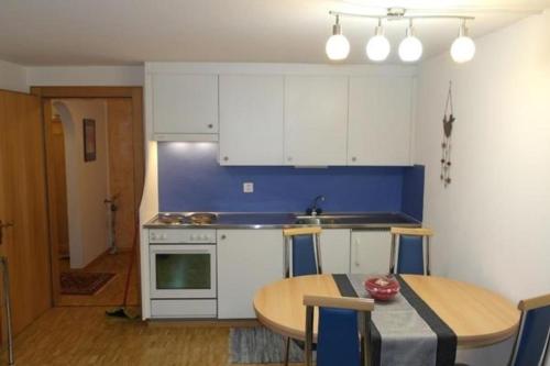 a kitchen with white cabinets and a table and a dining room at Ers Curtins in Zernez