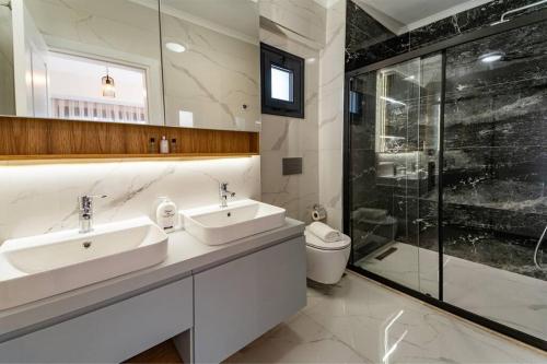 a bathroom with two sinks and a shower at merkezde 8 kişilik özel havuzlu villa in Fethiye