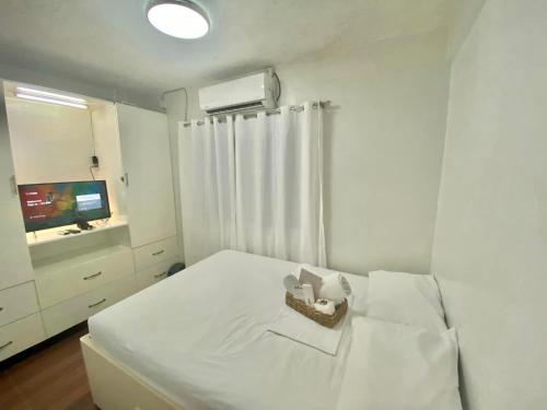 a white bedroom with a bed and a television at Tiny Room Hura Homes II Condominium Unit Visayas Avenue QC in Manila