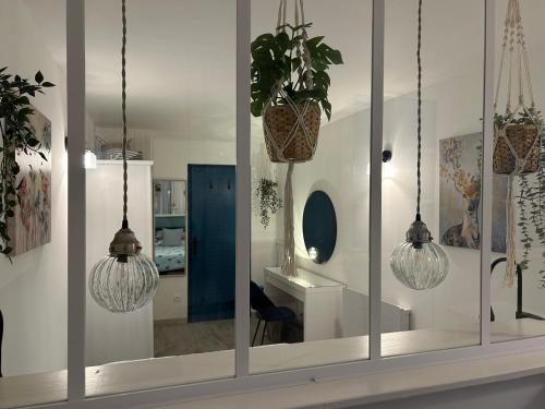 a room with three hanging lights and a mirror at La Petite Maison in Pont-d'Ouilly