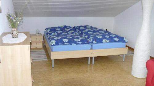 a bedroom with a bed with blue sheets and a table at Sunneggli in Aeschi bei Spiez