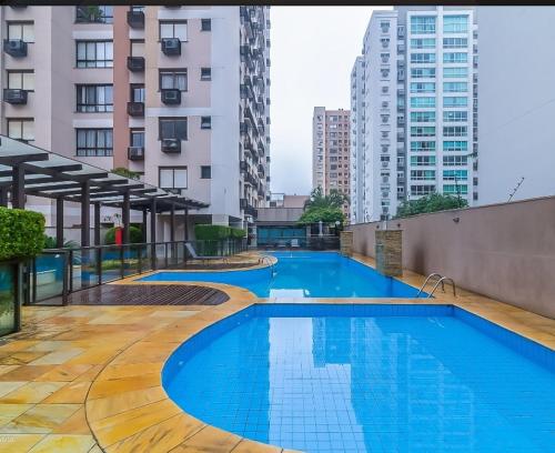 two swimming pools on the roof of a building with tall buildings at Aptoaconchegantepoa in Porto Alegre