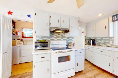 a kitchen with white cabinets and a stove top oven at Swift Beach House in Wareham