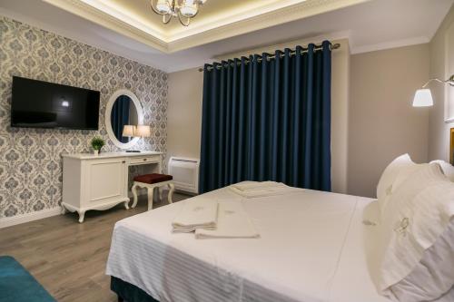a hotel room with a bed and a tv at Legacy Boutique Hotel in Korçë