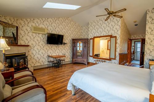 a bedroom with a white bed and a fireplace at Albergo Allegria Hotel & Breakfast Restaurant in Windham