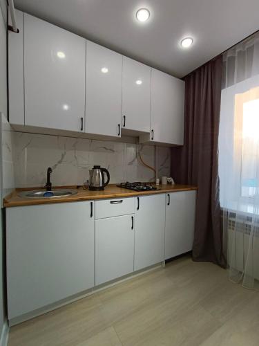 a kitchen with white cabinets and a sink at Квартира Алия in Aktobe