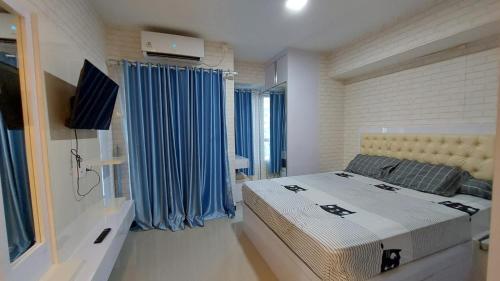 Schlafzimmer mit einem großen Bett und blauen Vorhängen in der Unterkunft Cozy Room by HHH PROPERTY in Jakarta