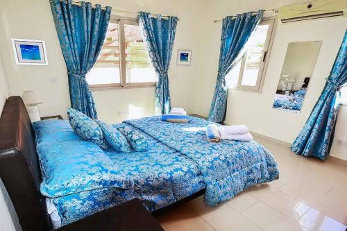 a bedroom with a blue bed with blue curtains at Villa Golden Coral in Peyia