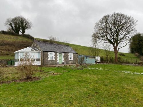 a small house on a hill with a green field at Ramulligan Cottage in Cavan