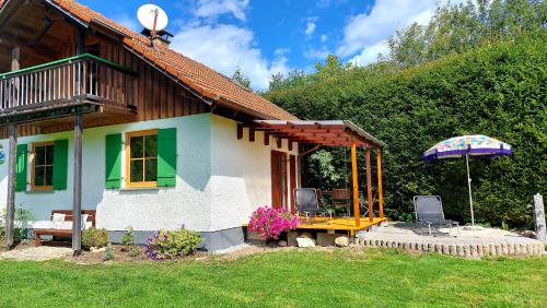 Casa pequeña con mesa y sombrilla en Ferienhaus auf dem Werteshof, en Peißenberg