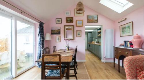 a dining room with pink walls and a table and chairs at Fletchers Cottage in Honiton