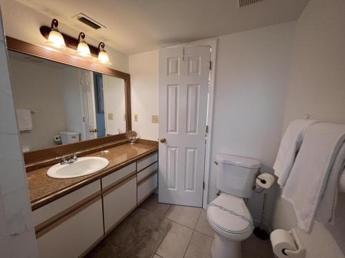 ein Badezimmer mit Toilette, Waschbecken und Spiegel in der Unterkunft Magical 3 Bed Condo at Sweetwater Club in Kissimmee