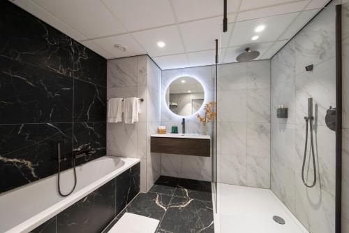 uma casa de banho com uma banheira, um lavatório e um espelho. em Bilderberg Hotel De Keizerskroon em Apeldoorn