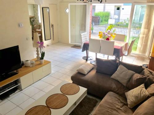 a living room with a brown couch and a tv at 80m2-Maison des quais - parking - jardinet in Rouen