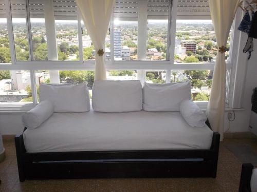 un sofá frente a una ventana con almohadas blancas en Mono ambiente miramar en Miramar