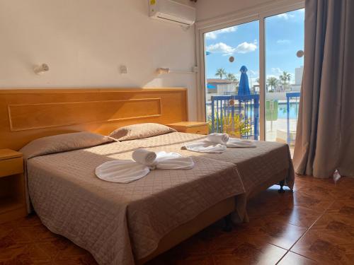 a bedroom with a bed with two towels on it at Alexia Hotel Apartments in Ayia Napa