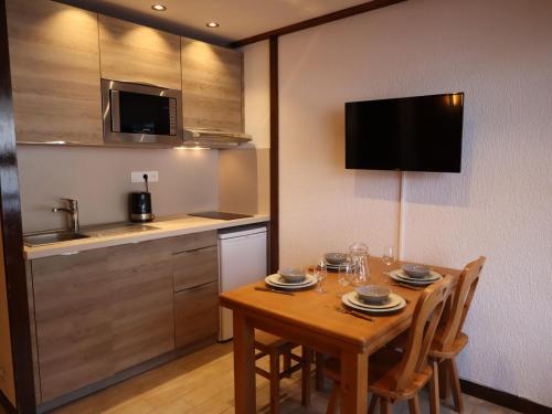 Il comprend une cuisine avec une table en bois, des chaises et une télévision. dans l'établissement Studio cosy au cœur des Gets, pied des pistes, refait à neuf, idéal famille! - FR-1-623-53, aux Gets