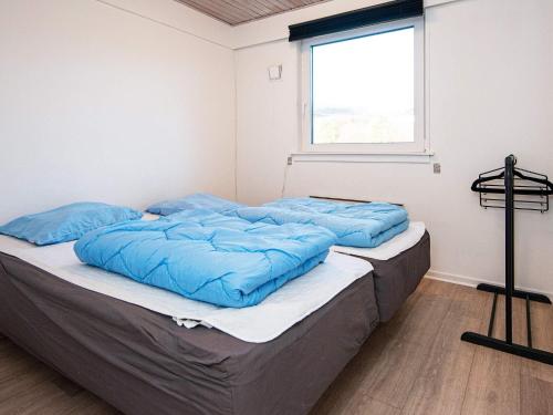Cette chambre dispose d'un lit avec des oreillers bleus et d'une fenêtre. dans l'établissement Comfortable Holiday Home in B rkop with Terrace, à Børkop