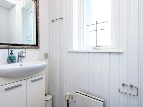 La salle de bains blanche est pourvue d'un lavabo et d'une croix sur la fenêtre. dans l'établissement Comfortable Holiday Home in B rkop with Terrace, à Børkop
