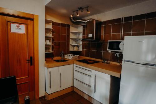 a kitchen with a white refrigerator and brown tiles at Apartamentos Boabdil in Sierra Nevada