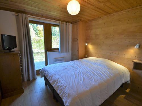 une chambre avec un lit dans une pièce avec une fenêtre dans l'établissement Appartement de standing calme, proche des pistes, avec balcon, terrasse, et garage privé aux Gets - FR-1-623-85, aux Gets