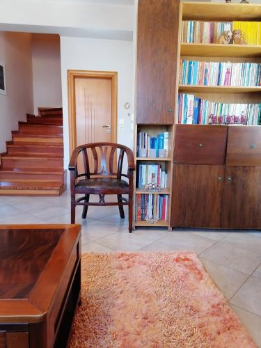 a living room with a chair and a book shelf with books at Homey Family ArtAki in Néa Artáki