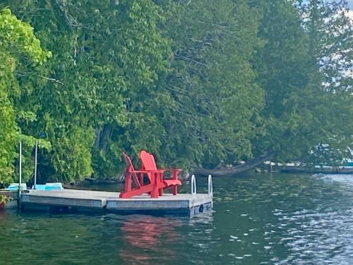 two red chairs sitting on a dock in the water at Chalet "Ici et maintenant, sur le lac" in Sainte-Marguerite