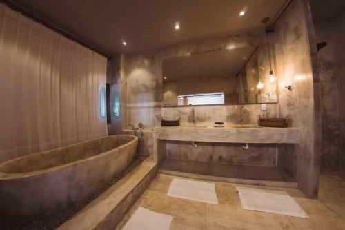 een badkamer met een groot bad en een grote spiegel bij Hotel Boutique Zebra Beach in Uruau