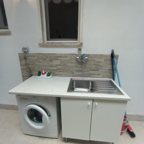 a kitchen with a sink and a washing machine at Appartamento Via Dei Glicini in Laigueglia
