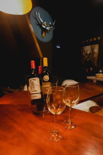 two wine bottles and two glasses on a wooden table at Apartamentos Boabdil in Sierra Nevada