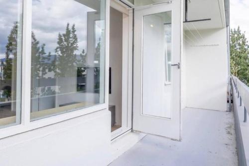 eine offene Tür zu einem Balkon mit Fenstern in der Unterkunft Cozy apartment in Akureyri in Akureyri
