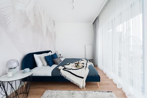 a bedroom with a blue bed and a white wall at Lake Club Apartments by LoftAffair in Mikołajki